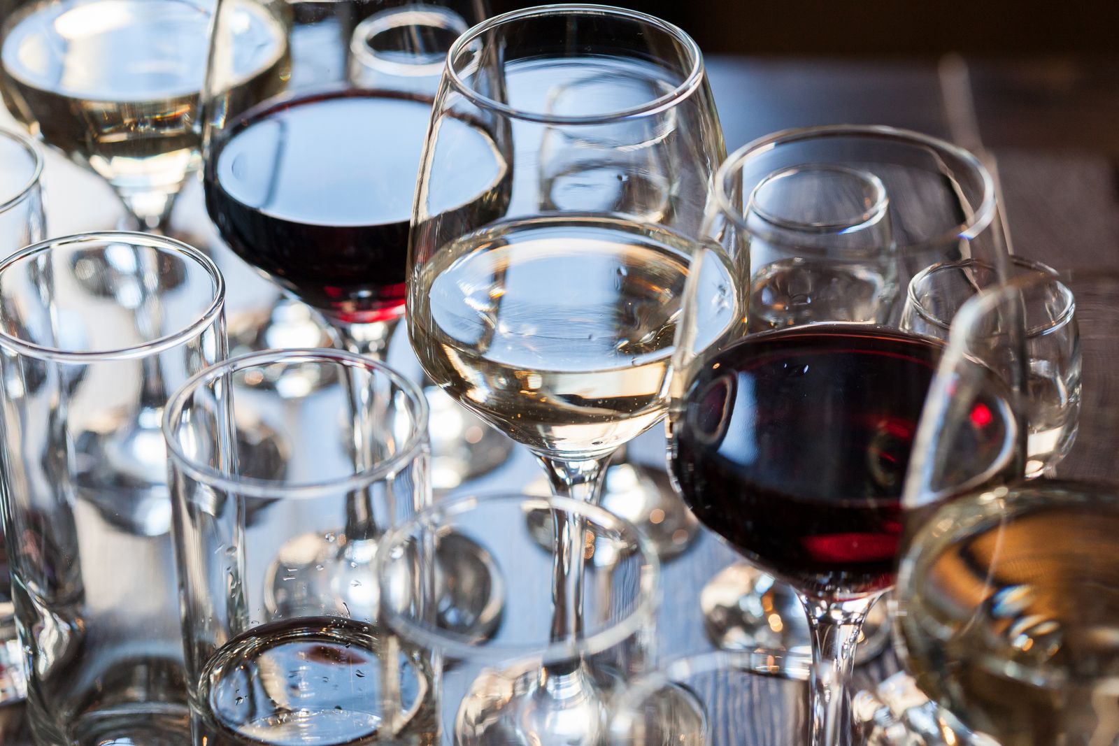Close-up of red and white wine in glasses on a table, with more glasses blurred behind